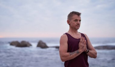 Fit genç adam alacakaranlıkta dramatik bir gökyüzüne karşı dua elleriyle ayakta iken onun yoga uygulaması sırasında meditasyon