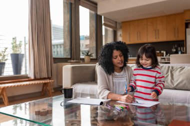 Gülümseyen anne ve onun sevimli küçük kız birlikte boya kalemleri ile boyama oturma odasında sehpa oturan