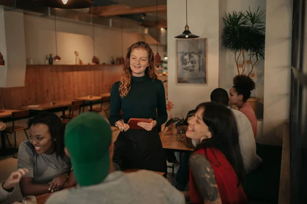 Усміхнена Офіціантка Приймає Замовлення Усміхненої Групи Різноманітних Молодих Друзів Сидячи — стокове фото