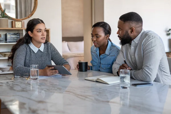 财务顾问与一对年轻的非洲裔美国夫妇在自家客厅的餐桌旁讨论储蓄计划 — 图库照片