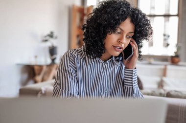 Genç bayan girişimci evde dizüstü bilgisayarla çalışırken bir müşterisiyle konuşuyor.