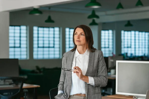 Gericht Zakenvrouw Met Haar Bril Kijken Diep Gedachten Terwijl Staan — Stockfoto