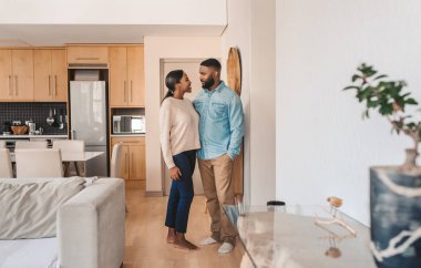 Genç Afro-Amerikan çift birbirlerine bakıp gülümserken birlikte oturuyorlar.