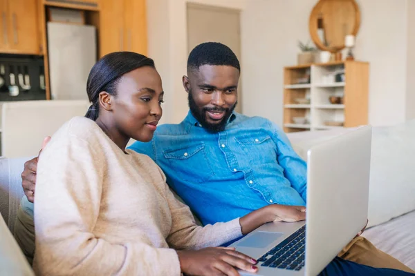 年轻的非洲裔美国人在家里的客厅沙发上 一边用笔记本电脑一边笑着 — 图库照片