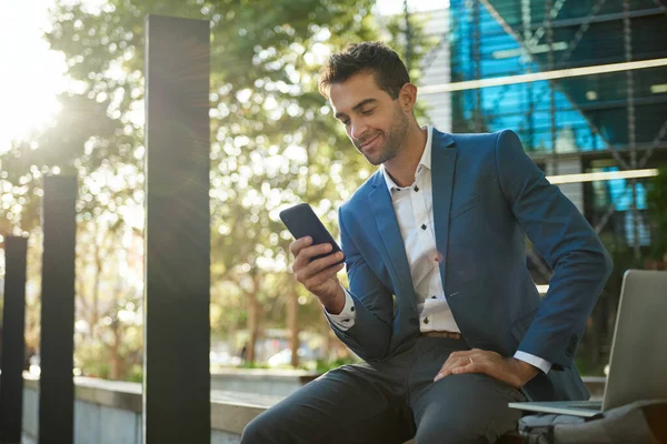 Sonriente Joven Hombre Negocios Sentado Fuera Edificio Oficinas Leyendo Mensaje —  Fotos de Stock