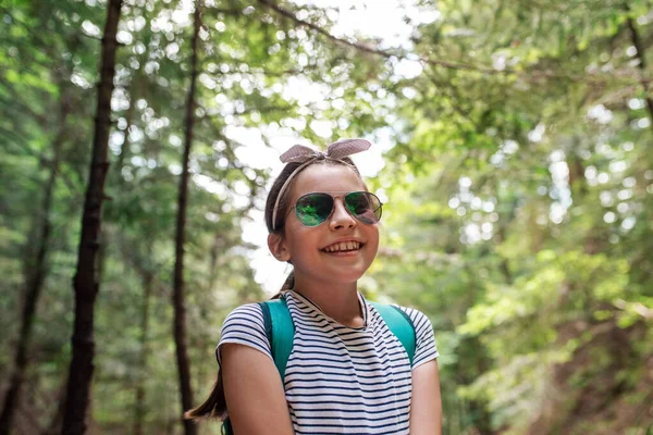 夏の森の中で一日歩くのを楽しみながらサングラスをかけ笑顔で愛らしい女の子 — ストック写真