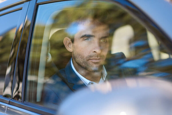 Молодой человек смотрит в окно водителя, сидя в машине в городе.