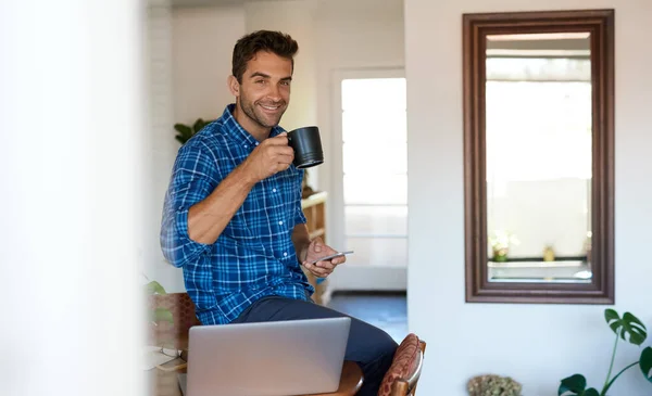 집에서 원격으로 일하는 커피를 마시고 핸드폰을 사용하는 미소를 젊은이의 — 스톡 사진