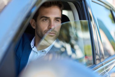 Genç adam şehirde araba kullanırken sürücü tarafından dışarı bakıyor.