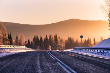 Kış dağlarında gün doğumunda arka plandaki yol.