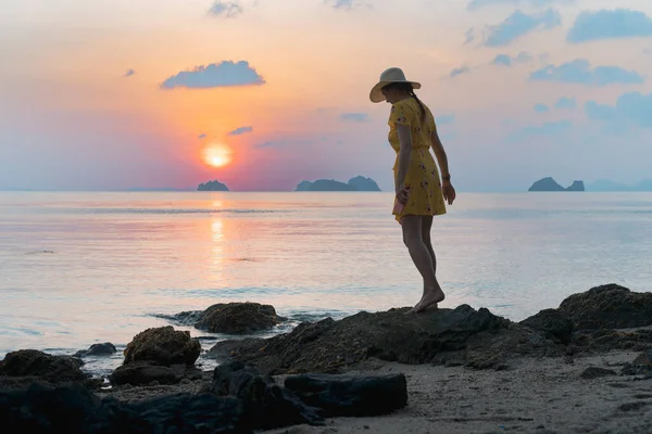 日落时分 年轻的高加索女人头戴黄帽 身穿黄衣 躺在沙滩上 望着落日 — 图库照片