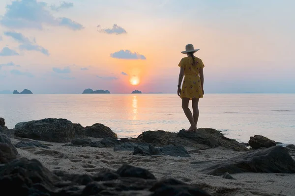 年轻的高加索女人 头戴黄帽 身穿黄衣 躺在沙滩上欣赏日落 — 图库照片