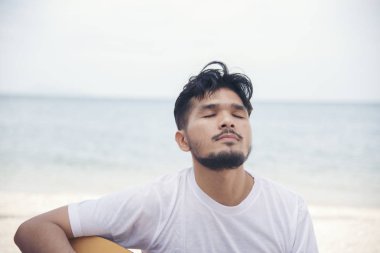 Sahilde gitar çalan adam. Klasik gitar çalan akustik müzisyen. Müzik konsepti.