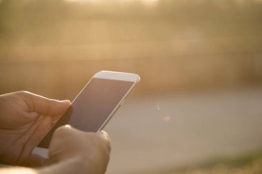 Güneş ışığı ile açık akıllı telefon kullanarak adamın ellerini kapatın.