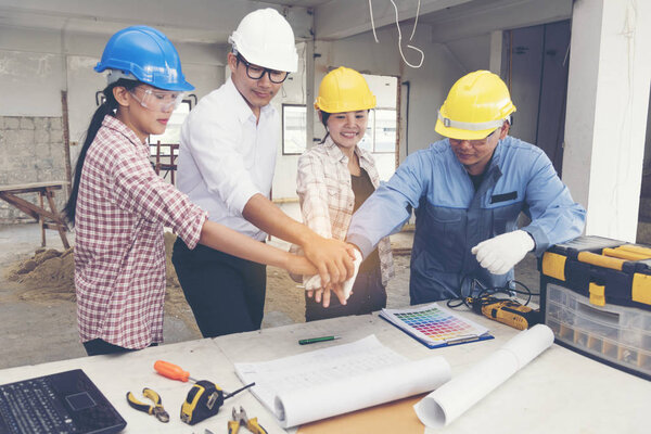 Construction teamwork shaking hands with engineer and foreman in construction site.