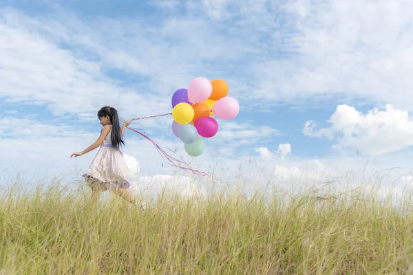 Счастливая Девушка Держит Красочные Воздушные Шары Зеленом Лугу Облачным Голубым — стоковое фото