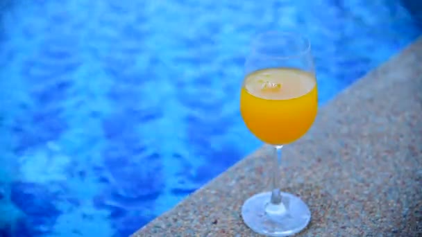 Despeje suco de laranja saudável para refrescar o copo de refrigerante saboroso e doce ao ar livre na piscina. Pomar de laranja fresco — Vídeo de Stock