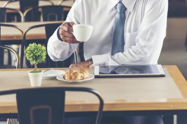Asyalı Yakışıklı işadamı dizüstü bilgisayar ile kahve dükkanında açık çalışan ve elinde kahve fincan tutarak. Wifi, kablosuz bağlantı ile teknolojiyi kullanarak ofis dışında çalışın. Teknoloji Kavramı.