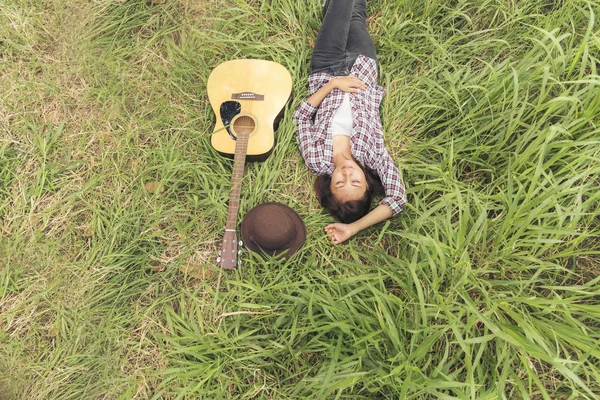 ギター楽器で牧草地に横たわる女性のトップビュー — ストック写真