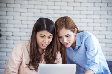 Mutlu girişimci Asyalı iş kadınları akıllı telefon pazarlığını yeni bir iş kurmak için kullanıyorlar. İki ortak akıllı telefonlardan iyi haberler alıyor. İş birliği yapan Asyalı kadın birlikte çalışıyor.