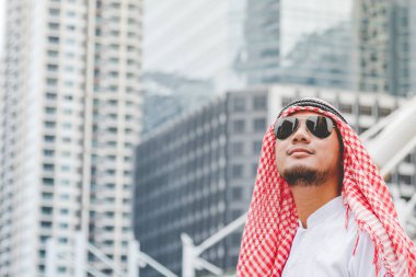 Akıllı tablet kullanan yakışıklı, modern Arap adam. Arap adam şehirde yürürken akıllı telefon kullanıyormuş. İş başarısı kavramları.