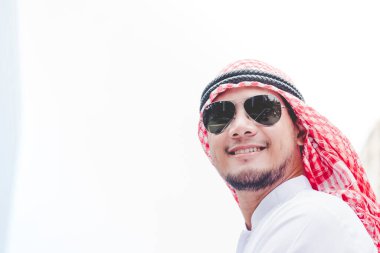Modern şehirde duran yakışıklı modern Arap adam ofis dışında türban takıyor ve etnik tebessüm takıyor. Arap adam büyük şehirde yürürken yeni bir proje planlıyor. İş başarılı