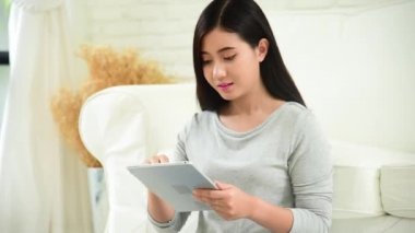 Asyalı kadın internet sitesinde akıllı telefondan tablet alışverişi yapıyor ve gülümsüyor.. 