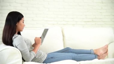 Asyalı kadın internet sitesinde akıllı telefondan tablet alışverişi yapıyor ve gülümsüyor.. 