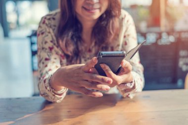 Asyalı bir kadın akıllı telefonlardan online alışveriş sitesini gülümseyen yüzüyle kullanıyor. Cep telefonu tutan Asyalı kadının mutluluğu İnternet alışveriş sitesinden gelen postaları kontrol etmesi Blog vlog sosyal medya yazısını okuması