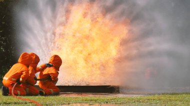 İtfaiyeci yangın hortumuyla, kimyasal köpüklü sprey motorla savaşıyor. İtfaiyeciler korunmak için kasketli, vücut korumalı üniformalı üniforma giyer. Yangın söndürücüde kurtarma eğitimi.