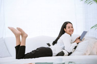 Asyalı bir kadın akıllı tablet el işaretli ekranlı dijital tablet üzerinde online telefon alışverişi yapıyor. Akıllı telefon tutan kadın İnternet alışveriş sitesinde e-postaları kontrol ediyor.