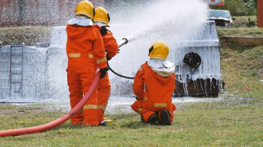 İtfaiyeci yangın hortumuyla, kimyasal köpüklü sprey motorla savaşıyor. İtfaiyeciler korunmak için kasketli, vücut korumalı üniformalı üniforma giyer. Yangın söndürücüde kurtarma eğitimi.