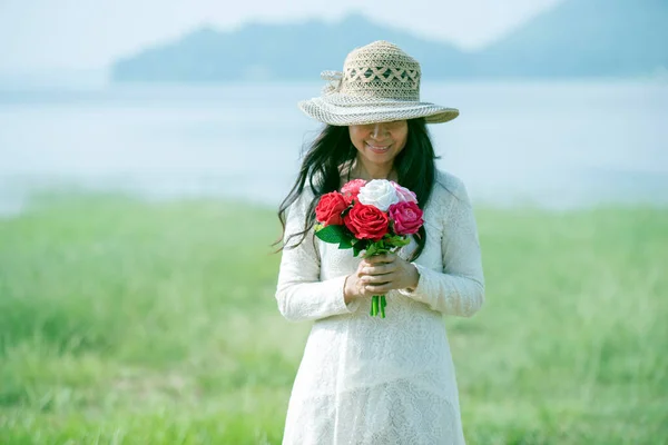 Holidays, love and flowers concept - young beautiful woman wear a white lace dress with bouquet of flowers.