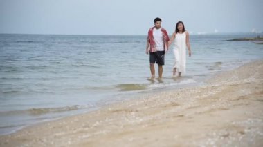 Balayı çifti aşığı kumsalda yürüyor romantik ilişki mutluluğu anı aşk yaşam tarzıyla. Sevgililer gününde sevgili olarak uzun bir kumsalda el ele yürür..