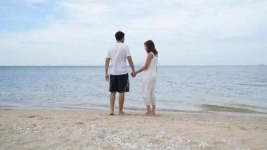 Balayı çifti aşığı kumsalda yürüyor romantik ilişki mutluluğu anı aşk yaşam tarzıyla. Sevgililer gününde sevgili olarak uzun bir kumsalda el ele yürür..