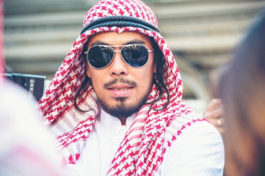 İslami Arap adam tesettür ve Müslüman resmi elbise giyer. Çok kültürlü iş adamları gülümser. Modern şehir manzarasında kameraya bakarlar..