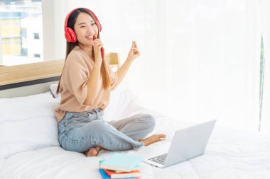 Sakin ol kadın yatakta okunan bir kitap tutuyor kulaklık kullanıyor, müzik dinliyor. Genç bir kadının rahatlaması, açık kitap gibi boş düşünceler okuyor. Mutluluk. Güzel kadın.