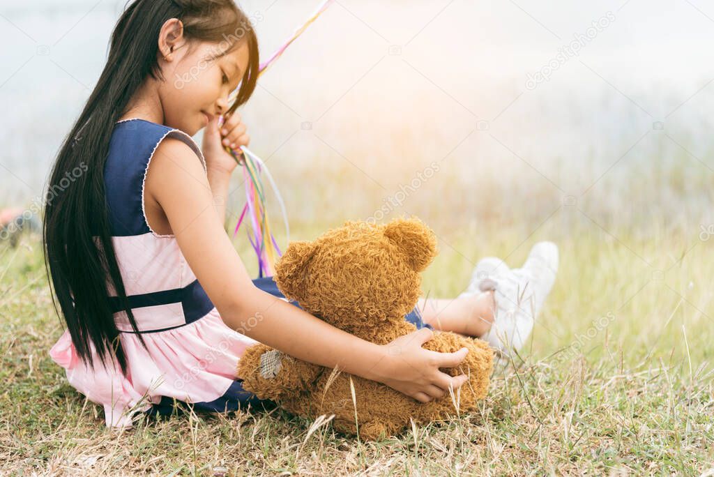 Happy Child hug teddy bear in green park playground. Teddy bear best friend for little kids cute girl. Autism happy funny playing together on playground in happiness family feel love and warm hugs