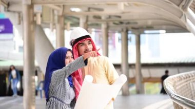 Arap mühendis, inşaat projesini birlikte yürüterek, inşaat sahasının altında ciddi bir sorun olan modern Müslüman BAE şehrine işaret ediyor. Çok kültürlü iş adamları konuşuyor.