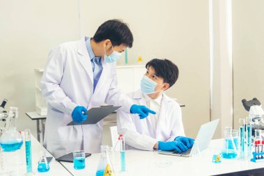 İki Asyalı bilim adamı kimya bilimi tüpü deney tüpü antikor örneğini kovid-19 virüsüne karşı laboratuvar geliştirmek için depoluyorlar. Kimya Laboratuarı 'nda bilim adamı danışmanı, analizi