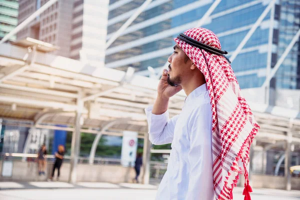 伊斯兰男子使用智能手机应用程序组织日程日程关注手握智能手机的穆斯林现代乌艾城市 阿拉伯男性穿着头巾和穆斯林的正式服装 发送短信 发送网上生活方式 — 图库照片