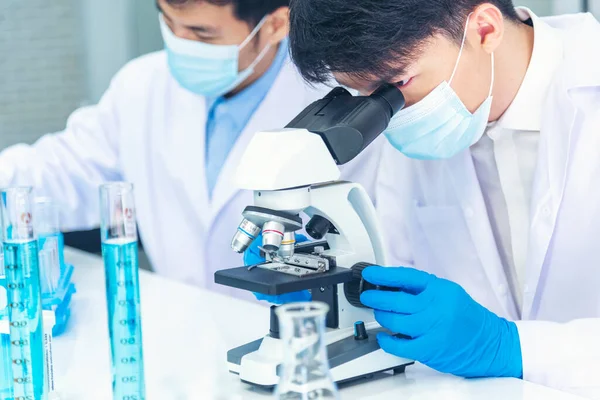 Two asian scientist team reserch chemistry science tube experiment biotech antibody sample in laboratory Cultivate Vaccine against covid-19 virus. Scientist consult, analyze in Chemistry Laboratory