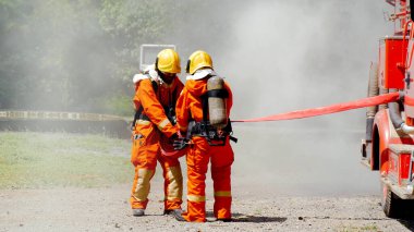 İtfaiyeci yangın hortumuyla, kimyasal köpüklü sprey motorla savaşıyor. İtfaiyeciler korunmak için kasketli, vücut korumalı üniformalı üniforma giyer. Yangın söndürücüde kurtarma eğitimi.