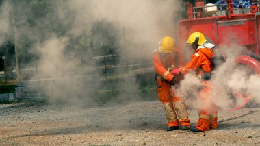 İtfaiyeci yangın hortumuyla, kimyasal köpüklü sprey motorla savaşıyor. İtfaiyeciler korunmak için kasketli, vücut korumalı üniformalı üniforma giyer. Yangın söndürücüde kurtarma eğitimi.
