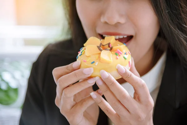 Happy woman eat cake delicious sweet dessert in chocolate cafe. Asian woman holding fork eating sweet fancy cake sugar tasty plate in coffee shop. Woman sitting on cozy sofa holding sweet cupcake