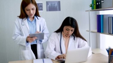 Hastane sağlık tedavi kliniğinde uzman doktorlara danışmanlık yapan iki kadın doktor. Doktor, dizüstü bilgisayar kullanarak onkolog tedavisi için reçete yazıyor.. 