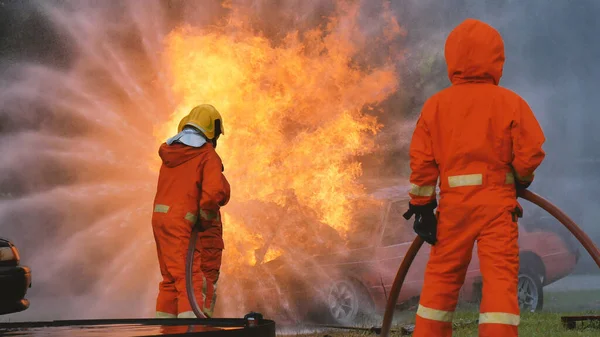 Firefighter fighting with flame using fire hose chemical water foam spray engine. Fireman wear hard hat, body safe suit uniform for protection. Rescue training in fire fighting extinguisher