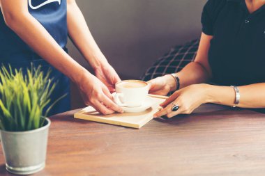 Kahve dükkanında taze sıcak Cappuccino kahve fincanı servis ediliyor. Garsonun ellerini kapat ve müşteriye servis yap..