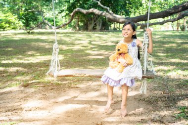 Yeşil Park 'ta oyuncak ayıya sarılırken mutlu çocuk. Oyuncak ayı, küçük çocuklar için en iyi arkadaş tatlı kız. Otizm mutlu bir şekilde oyun bahçesinde birlikte oynayarak mutlu bir aile sevgisi ve sıcacık kucaklaşmayı hisseder.