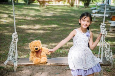 Yeşil Park 'ta oyuncak ayıya sarılırken mutlu çocuk. Oyuncak ayı, küçük çocuklar için en iyi arkadaş tatlı kız. Otizm mutlu bir şekilde oyun bahçesinde birlikte oynayarak mutlu bir aile sevgisi ve sıcacık kucaklaşmayı hisseder.